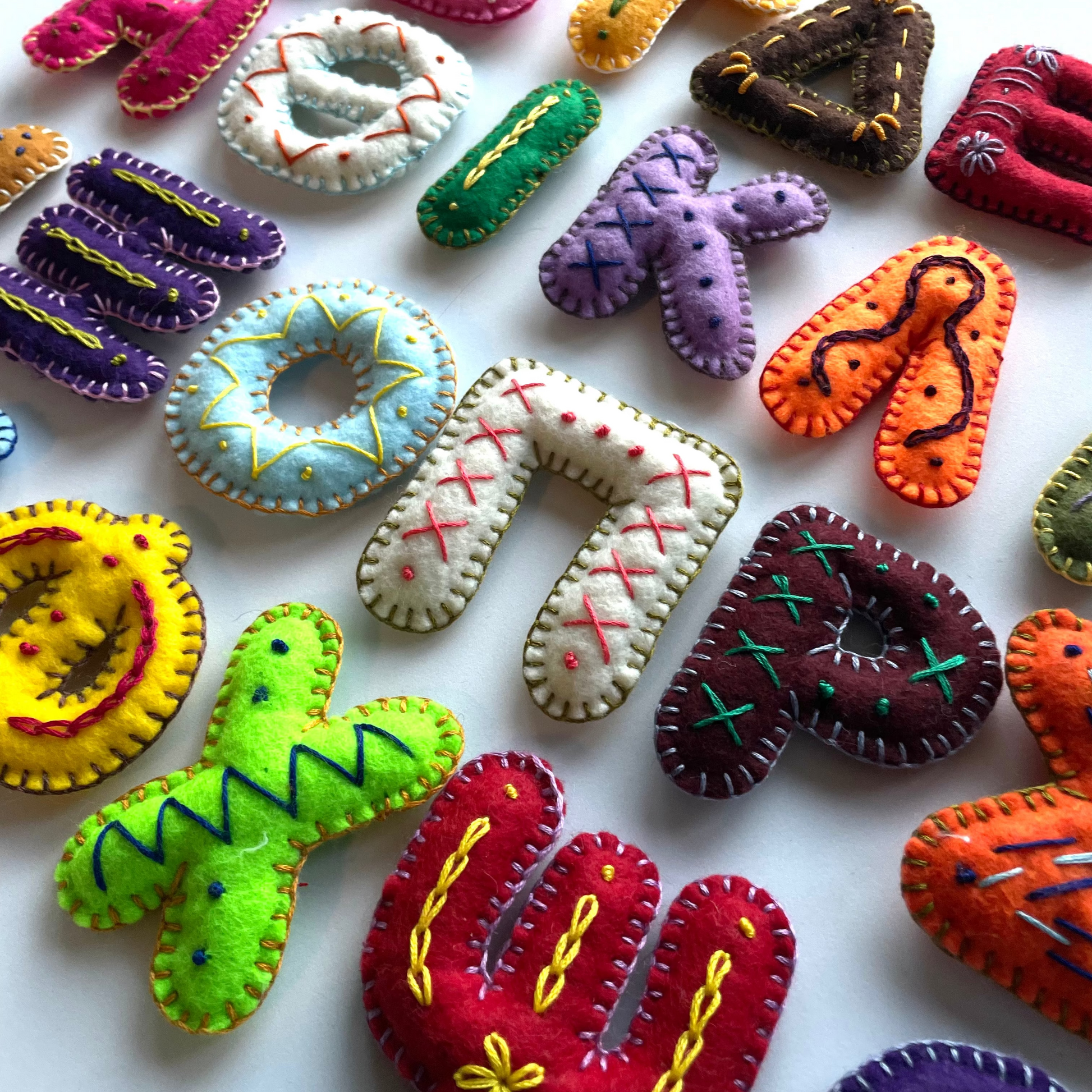 Colorful Greek handmade felt letters and shapes on a white background