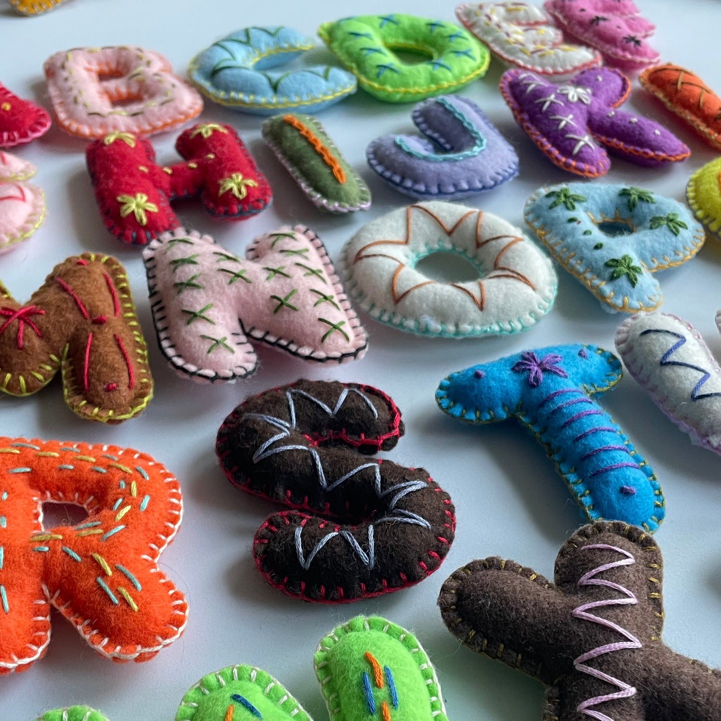 Colorful handmade felt letters and shapes on a white background