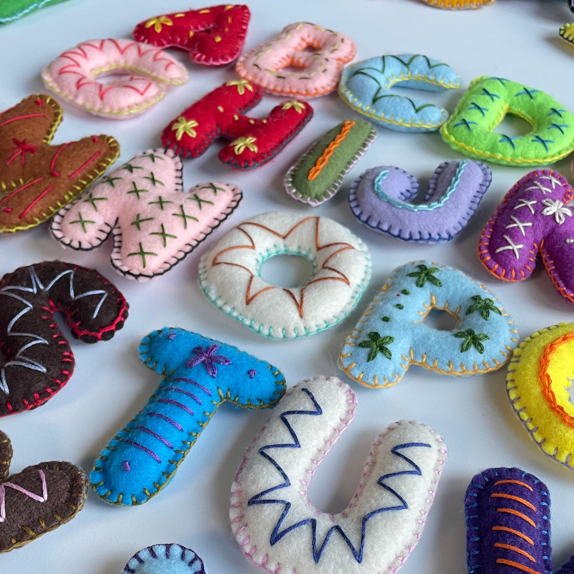 Colorful handmade felt letters and shapes on a white background