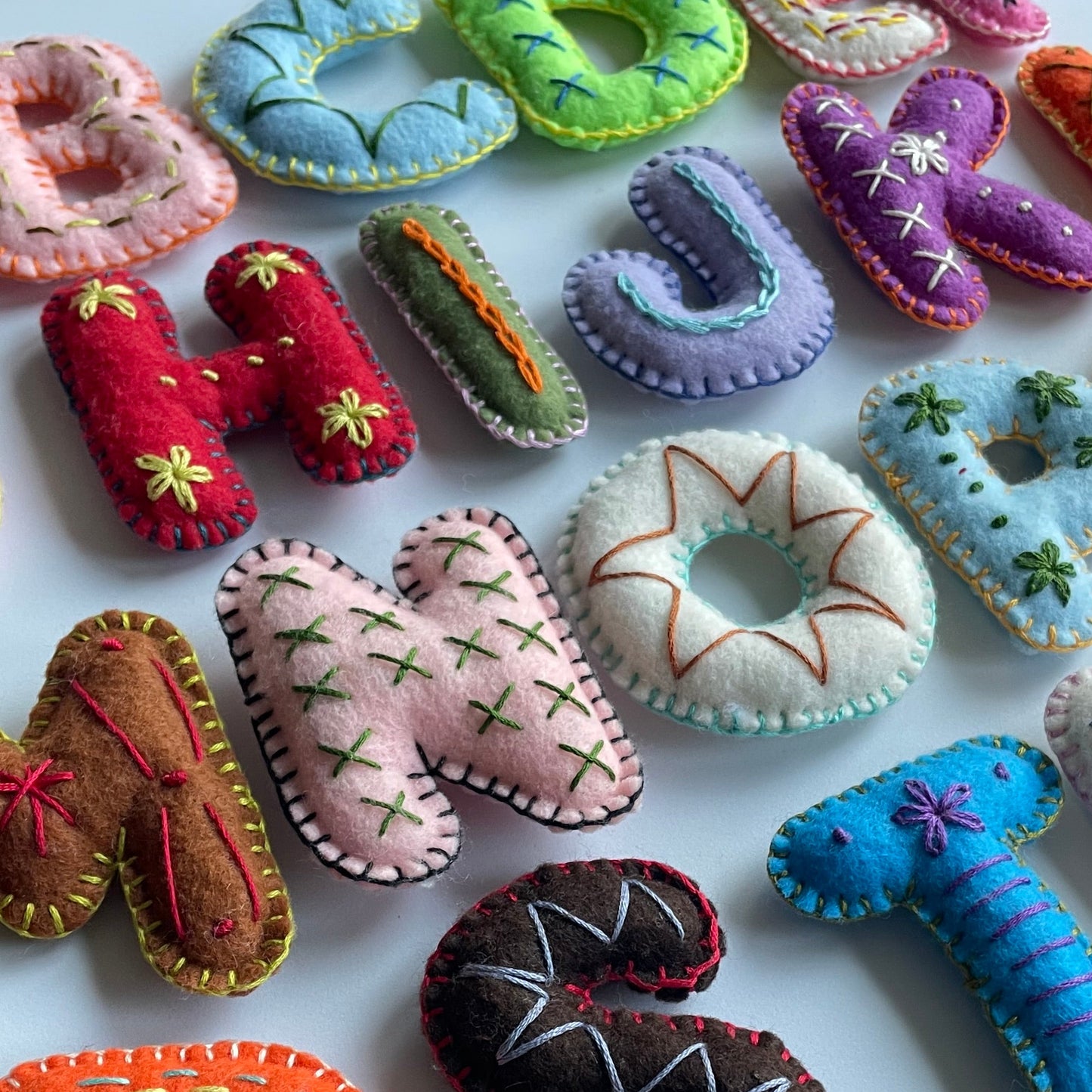 embroidered stuffed handmade felt letters on a white background