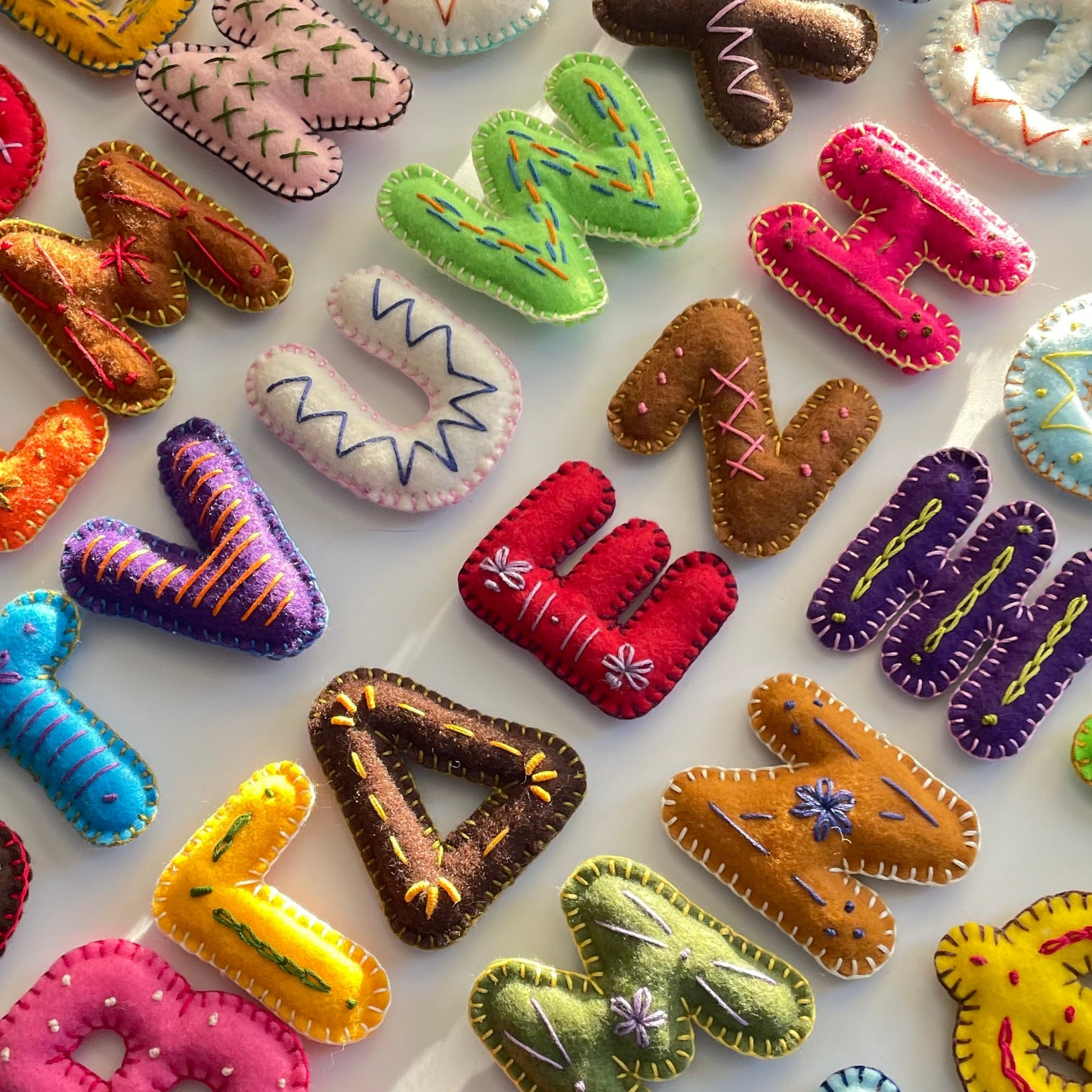 Colorful handmade  letter-shaped objects on a white background