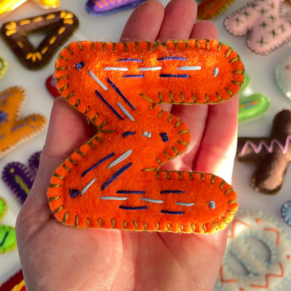 Hand holding a Greek Letter Sigma orang with colorful letters in the background